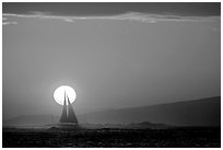 Sailboat and sun disk, sunset. Waikiki, Honolulu, Oahu island, Hawaii, USA ( black and white)