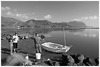 Fisherman and family pulling out net out of small baot, Kaneohe Bay, morning. Oahu island, Hawaii, USA (black and white)