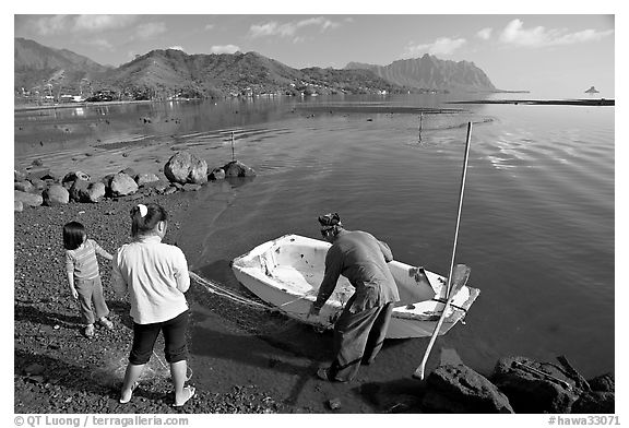 Fisherman with family and small baot, Kaneohe Bay, morning. Oahu island, Hawaii, USA (black and white)