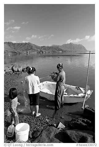 Fishing family working around small baot, Kaneohe Bay, morning. Oahu island, Hawaii, USA (black and white)