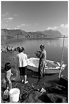 Fisherman and family pulling out net out of small baot, Kaneohe Bay, morning. Oahu island, Hawaii, USA (black and white)