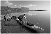 Man loading sea kayak for a fishing trip, Kaneohe Bay, morning. Oahu island, Hawaii, USA (black and white)