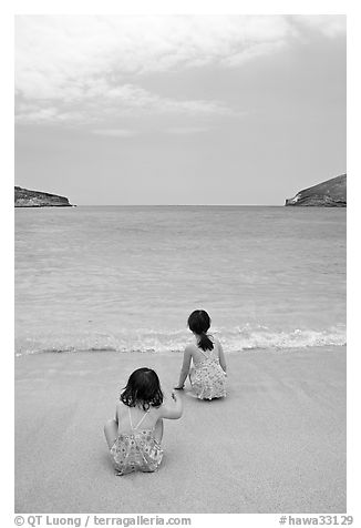 Two girls at the edge of water, Hanauma Bay. Oahu island, Hawaii, USA (black and white)