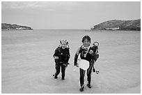 Scuba divers walking out of the water, Hanauma Bay. Oahu island, Hawaii, USA (black and white)
