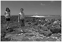 Girls playing in tidepool, Kukuila. Kauai island, Hawaii, USA (black and white)