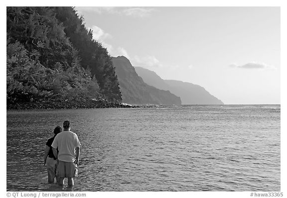 Couple standing in water, Kee Beach, late afternoon. Kauai island, Hawaii, USA (black and white)