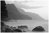 Boulders, surf, and Na Pali cliffs, sunset. Kauai island, Hawaii, USA ( black and white)