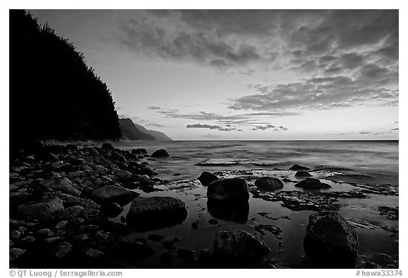 Boulders, surf, and Na Pali Coast, dusk. Kauai island, Hawaii, USA