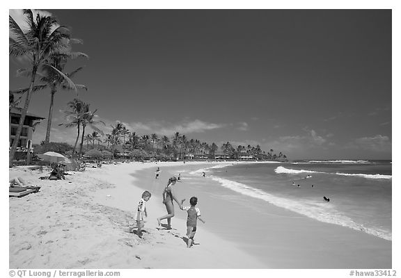 Children playing around, Kiahuna Beach, mid-day. Kauai island, Hawaii, USA (black and white)