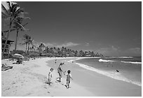 Children playing around, Kiahuna Beach, mid-day. Kauai island, Hawaii, USA (black and white)