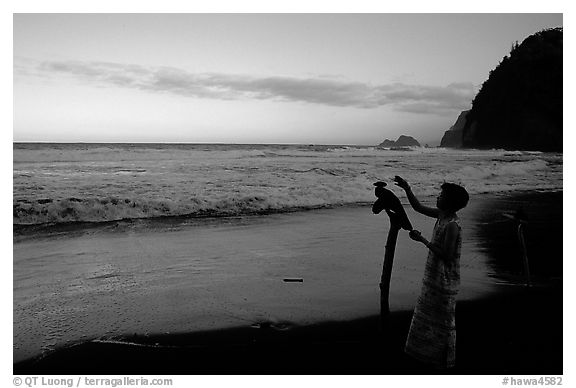 Hawaiian woman piles a stone on a stick as a traditional gesture of reverence, Polulu Beach. Big Island, Hawaii, USA (black and white)