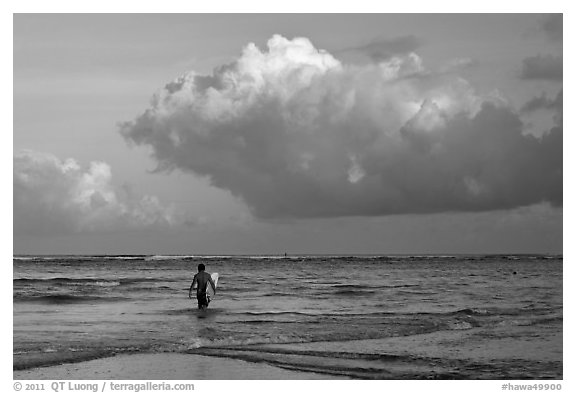 Surfer heading out in ocean. Kauai island, Hawaii, USA (black and white)
