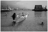 Girls, outrigger canoe, and Kamakahonu heiau, Kailua-Kona. Hawaii, USA (black and white)