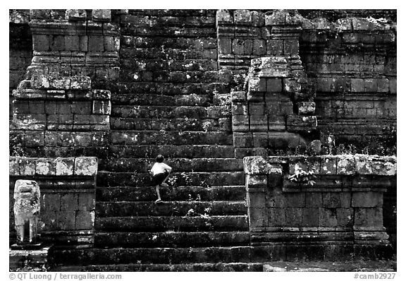 Boy climbs near-vertical staircase, Angkor Thom complex. Angkor, Cambodia (black and white)