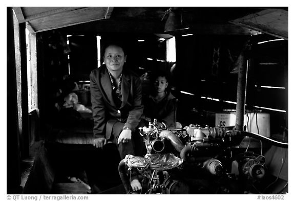 Engine and pilot at the rear of a slow passenger boat. Mekong river, Laos (black and white)