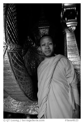 Buddhist novice monk, grinning because demonstrating ordained monks style of robe draping. Luang Prabang, Laos (black and white)