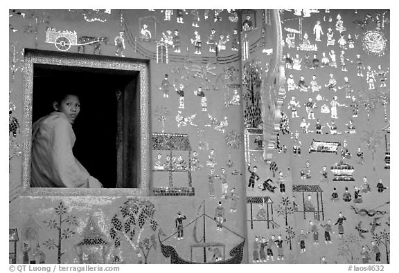 Buddhist novice monk sits at window of shrine, Wat Xieng Thong. Luang Prabang, Laos (black and white)