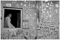 Buddhist novice monk sits at window of shrine, Wat Xieng Thong. Luang Prabang, Laos (black and white)