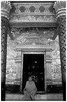 Buddhist novice monk sits at door of Wat Mai Suwannaphumaham. Luang Prabang, Laos ( black and white)