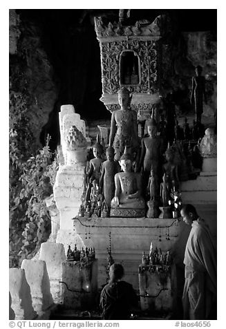 Novice Buddhist monk and vistor in Pak Ou cave. Laos (black and white)