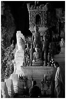 Novice Buddhist monk and vistor in Pak Ou cave. Laos (black and white)