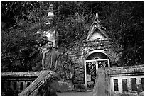 Novice Buddhist monk at entrance of cave, Pak Ou. Laos (black and white)