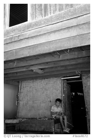 Boy at the entrance of traditional hut, Ban Xang Hai. Laos (black and white)