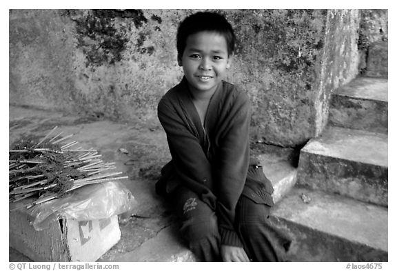 Boy sells incence sticks at the entrance of a shrine, Pak Ou. Laos (black and white)