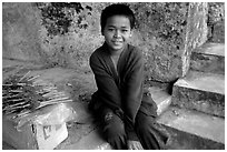 Boy sells incence sticks at the entrance of a shrine, Pak Ou. Laos (black and white)