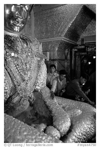 Adding golden leaves to the venerated Mahamuni image. Mandalay, Myanmar (black and white)