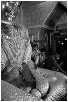 Adding golden leaves to the venerated Mahamuni image. Mandalay, Myanmar (black and white)