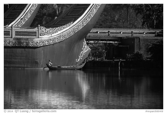 Man rowing boat next to Karawek barge. Yangon, Myanmar (black and white)