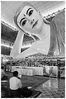 Men praying in front of reclining Buddha statue, Kyauk Htat Gyi Pagoda. Yangon, Myanmar ( black and white)