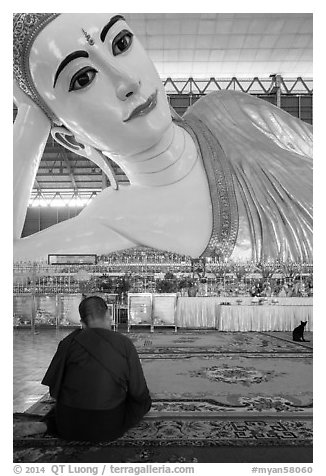 Monk praying in front of reclining Buddha statue, Kyaukhtatgyi Pagoda. Yangon, Myanmar (black and white)