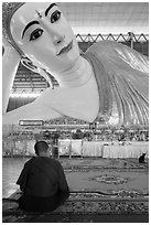 Monk praying in front of reclining Buddha statue, Kyaukhtatgyi Pagoda. Yangon, Myanmar ( black and white)