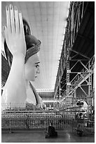 Monk and reclining Buddha statue housed in large metal shed, Kyauk Htat Gyi Pagoda. Yangon, Myanmar ( black and white)