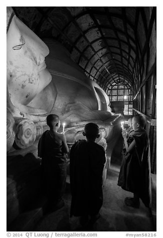 Novices standing with candles next to Shin Bin Thal Yaung reclining Budddha. Bagan, Myanmar (black and white)