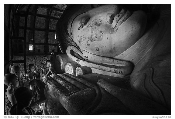 Young monks with candles worship Shin Bin Thal Yaung reclining Budddha. Bagan, Myanmar (black and white)