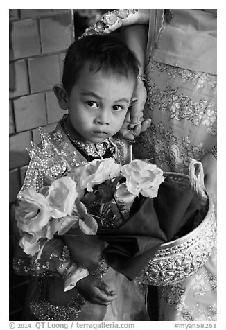 Child carrying offering bowl and flowers for novitiation ceremony, Mahamuni Pagoda. Mandalay, Myanmar (black and white)