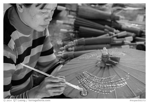 Woman painting the red umbrellas carried by the monks. Pindaya, Myanmar (black and white)