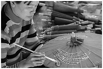 Woman painting the red umbrellas carried by the monks. Pindaya, Myanmar ( black and white)