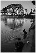 Women washing and doing laundry in lake with pagoda in background. Pindaya, Myanmar ( black and white)