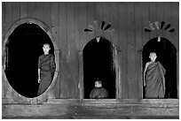 Buddhist monks looking through windows of Shweyanpyay Monastery, Nyaung Shwe. Inle Lake, Myanmar ( black and white)