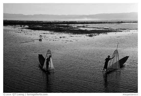 Intha fishermen row with backlit conical nets. Inle Lake, Myanmar (black and white)