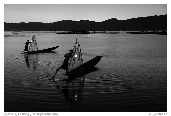 Leg-rowing Intha fishermen with lanterns at dusk. Inle Lake, Myanmar (black and white)