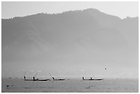 Intha fishermen in the distance using spears to stir fish, below tall hills. Inle Lake, Myanmar ( black and white)
