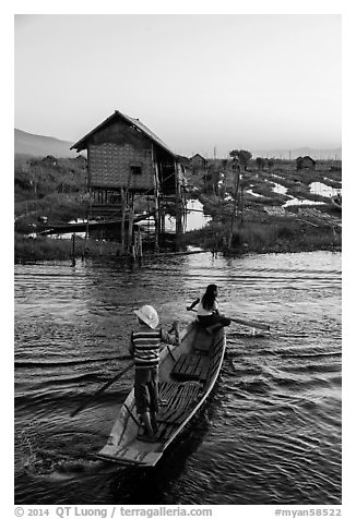 Children rowing across canal towards floating gardens, Maing Thauk Village. Inle Lake, Myanmar (black and white)