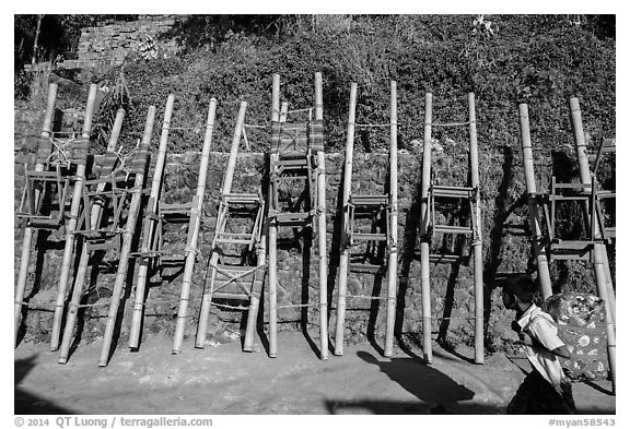 Child walking past sedan chairs. Kyaiktiyo, Myanmar (black and white)