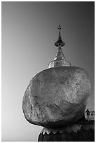 Pilgrim prays to the gleaming Golden Rock at sunset. Kyaiktiyo, Myanmar ( black and white)