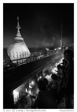 Pilgrims light up candles behind the Golden Rock at dusk. Kyaiktiyo, Myanmar (black and white)